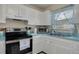 Well-lit kitchen with white cabinets, updated appliances, and a stainless steel sink at 21078 Sw Honeysuckle St, Dunnellon, FL 34431