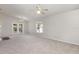 Large open living room with carpeted floors, French doors, ceiling fans, and a green view outside the window at 3235 Grand Pines Dr, Lakeland, FL 33810