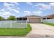 Exterior view of house with a white fence, a driveway, and an attached garage at 3321 Pintello Ave, New Smyrna Beach, FL 32168