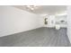 Spacious living room showcasing gray wood-look floors, white walls, and an open layout leading into the kitchen at 781 Poppy Ln, Dundee, FL 33838