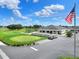 View of the golf course, clubhouse, and golf cart parking area with the American flag in view at 1074 Canary S Cir, Lakeland, FL 33809