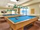 Well-lit game room featuring billiard tables with green shaded lamps and natural light from large windows at 1074 Canary S Cir, Lakeland, FL 33809