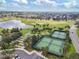 Aerial view showcasing community amenities, including tennis courts, a lake, and lush landscaping at 879 Astor Way, The Villages, FL 32162