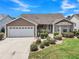 Charming single-story home with a well-manicured lawn, attached garage, and inviting front entrance at 879 Astor Way, The Villages, FL 32162