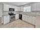 Updated kitchen showcasing stainless steel appliances, tiled backsplash, and white cabinetry at 879 Astor Way, The Villages, FL 32162