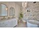 Luxurious bathroom with a freestanding tub, stone accent wall, double vanity, and stylish chandelier at 359 Terminal Ave, Polk City, FL 33868
