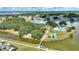 Aerial view of community featuring lake, green spaces, pool, and tennis courts at 4709 Club Cir, Lakeshore, FL 33854