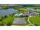 Beautiful aerial view of community pool, tennis courts, and clubhouse near lake with lush landscaping at 5660 Elsinore Way, Lakeland, FL 33805