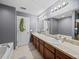 Bathroom with dual sinks, wood cabinets, updated lighting, and neutral countertops at 5660 Elsinore Way, Lakeland, FL 33805