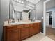 Bathroom with dual sinks, wood cabinets, updated lighting, and neutral countertops at 5660 Elsinore Way, Lakeland, FL 33805
