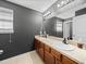 Bathroom with dual sinks, wood cabinets, updated lighting, and neutral countertops at 5660 Elsinore Way, Lakeland, FL 33805