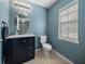 Cozy half bathroom features a vanity with storage, white toilet, and a window for natural light at 5660 Elsinore Way, Lakeland, FL 33805