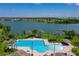 Aerial view of a large community pool by a lake, featuring ample seating and lush palm trees at 5660 Elsinore Way, Lakeland, FL 33805