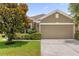 Exterior home shot highlighting the neutral color scheme, lush landscaping and a 2 car garage at 1111 Bassano Way, Orlando, FL 32828