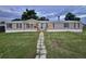 Charming single-story home with gray siding, black shutters, a lush front lawn, and a stone walkway at 5790 Cherry Tree Dr, Lakeland, FL 33811
