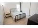 This cozy bedroom features neutral colors, natural light, a black metal bed frame, and wood-look flooring at 10274 Julia Isles Ave, Oxford, FL 34484