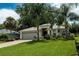 Well-maintained home featuring verdant lawn, mature palms, paver driveway, and attached garage at 10274 Julia Isles Ave, Oxford, FL 34484