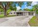Single-story home with attached carport and enclosed porch on a large driveway surrounded by mature trees at 107 Alachua Dr, Winter Haven, FL 33884