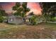Charming single-story home features a mature tree, tidy landscaping, and a carport on a partly cloudy day at 107 Alachua Dr, Winter Haven, FL 33884