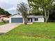 Charming single-story home with a well-manicured lawn, blue garage door, and mature trees at 299 Cobalt Dr, Kissimmee, FL 34758