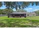 View of the back of the house with pool, large yard and mature trees at 4621 Musket Dr, Lakeland, FL 33810