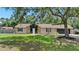 Charming single-story home featuring a stone facade, manicured lawn, and mature trees at 4621 Musket Dr, Lakeland, FL 33810
