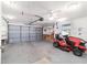Garage featuring a gray door, a lawn mower, and shelving units at 8851 Sw 116Th Street Rd, Ocala, FL 34481