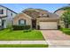 Charming single-Gathering home featuring a stone accent wall, brick driveway, manicured lawn, and a two-car garage at 1138 Fountain Coin Loop, Orlando, FL 32828