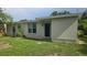 Home backyard featuring green grass, a window, AC unit, and a black entry door at 1514 Crest Ave, Leesburg, FL 34748
