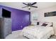 Vibrant bedroom with a purple accent wall, a cozy bed, and a modern entertainment setup for relaxation at 1518 Louise Ave, Auburndale, FL 33823