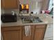 A kitchen with wooden cabinets, stainless steel sink, and a black microwave at 606 Carrigan Woods Trl, Oviedo, FL 32765