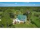 Aerial view of a beautiful country home with a green metal roof surrounded by lush greenery and trees at 10222 Rockridge Rd, Lakeland, FL 33810