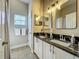 Well-lit bathroom featuring a double vanity, black countertop and a window at 10222 Rockridge Rd, Lakeland, FL 33810