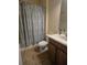 Functional bathroom featuring a toilet, sink with cabinet, and a shower with blue patterned curtain at 8923 Cuban Palm Rd, Kissimmee, FL 34747