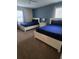 Inviting bedroom with two beds, soft carpet, and a calming blue accent wall at 8923 Cuban Palm Rd, Kissimmee, FL 34747