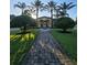 Brick walkway leads to home with manicured lawn, hedges, and framed by multiple towering palm trees at 8923 Cuban Palm Rd, Kissimmee, FL 34747