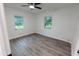 Bright bedroom featuring gray wood flooring, crisp white walls, and an overhead fan at 1400 E Fern Rd, Lakeland, FL 33801