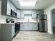 Updated kitchen featuring stainless steel appliances, sleek gray cabinets, and gray wood flooring at 1400 E Fern Rd, Lakeland, FL 33801