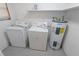Well-lit laundry area equipped with washer, dryer, water heater, and overhead shelving at 1400 E Fern Rd, Lakeland, FL 33801