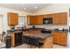 Features light wood cabinets, black appliances, an island with bar seating, and backsplash at 643 Blenheim Loop, Winter Springs, FL 32708