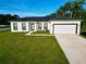 Beautiful single Gathering home featuring a two-car garage, lush green lawn, and a stylish white exterior at 1430 Tern Ct, Poinciana, FL 34759