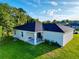 Rear exterior of home with a covered patio, lush green lawn, and dark roof at 1430 Tern Ct, Poinciana, FL 34759