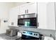 Modern kitchen featuring stainless steel microwave, white cabinets, and patterned backsplash at 1430 Tern Ct, Poinciana, FL 34759