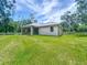 View of the rear of the home from the backyard featuring a covered patio and lush lawn at 5080 Maple Dr, Lakeland, FL 33810