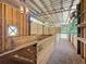 An interior view of a barn featuring wooden stalls, gravel flooring, and open design at 5080 Maple Dr, Lakeland, FL 33810