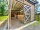 An open barn with a sliding wooden door, gravel floor, and wooden stalls at 5080 Maple Dr, Lakeland, FL 33810
