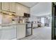 Kitchenette with white cabinets, stainless steel mini fridge, and view into the bedroom with two beds at 6165 Carrier Dr # 1309, Orlando, FL 32819