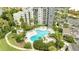 An aerial view of a large clover shaped community pool surrounded by lush landscaping and a high rise building at 6165 Carrier Dr # 1309, Orlando, FL 32819