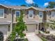 Exterior view of a two-story townhome featuring a garage, well-maintained landscaping, and a covered entry at 67 Bella Oaks Dr, Port Orange, FL 32129