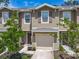 Exterior view of a two-story townhome featuring a garage, well-maintained landscaping, and a covered entry at 67 Bella Oaks Dr, Port Orange, FL 32129